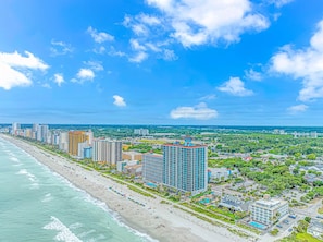 Un paisaje urbano costero con rascacielos, una playa y cielo despejado.