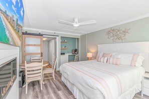 A bedroom with a bed, a desk, a chair, a ceiling fan, and a wall with starfish decorations.