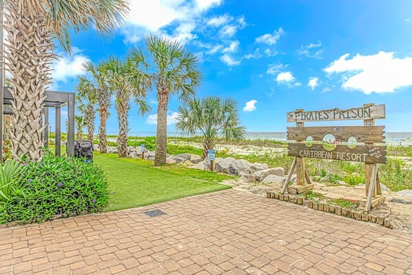 A sign for Pirates Prison Caribbean Resort with palm trees and a beach in the background.