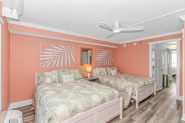Un dormitorio con dos camas, un ventilador de techo y una mesita de noche con lámpara.