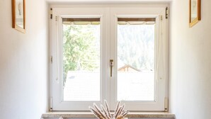 A wooden bench with a decorative vase and a candle, positioned under a window with a view of greenery outside. - Apartment Rosengarten (Tiers)