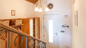 A wooden staircase with a metal railing, a ceiling fan, and a door with a light switch on the wall. - Apartment Rosengarten (Tiers)
