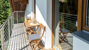 A wooden balcony with a table and chairs, a view of the surrounding landscape, and a large window. - Apartment Rosengarten (Tiers)