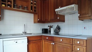 Een keuken met houten kastjes, een vaatwasser, een magnetron en een inbouwoven.