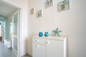Un couloir avec une armoire blanche, des étoiles de mer décoratives et des tableaux encadrés accrochés au mur.