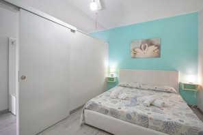 Une chambre à coucher avec un lit, une porte et un mur orné d’un tableau.
