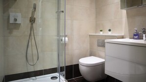 A modern bathroom with a glass shower enclosure, a white toilet, and a sink with a mirror above.