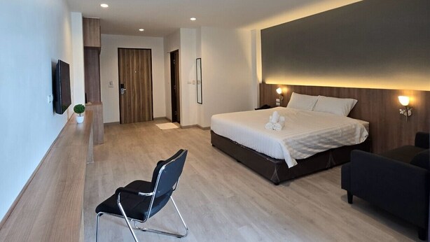 A modern hotel room with a large bed, a desk, and a chair.