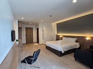 A modern hotel room with a large bed, a desk, and a chair. - Manee Mantra Hotel Kanchanaburi (Kanchanaburi)