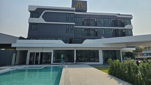 A modern multi-story building with a large pool area in front.