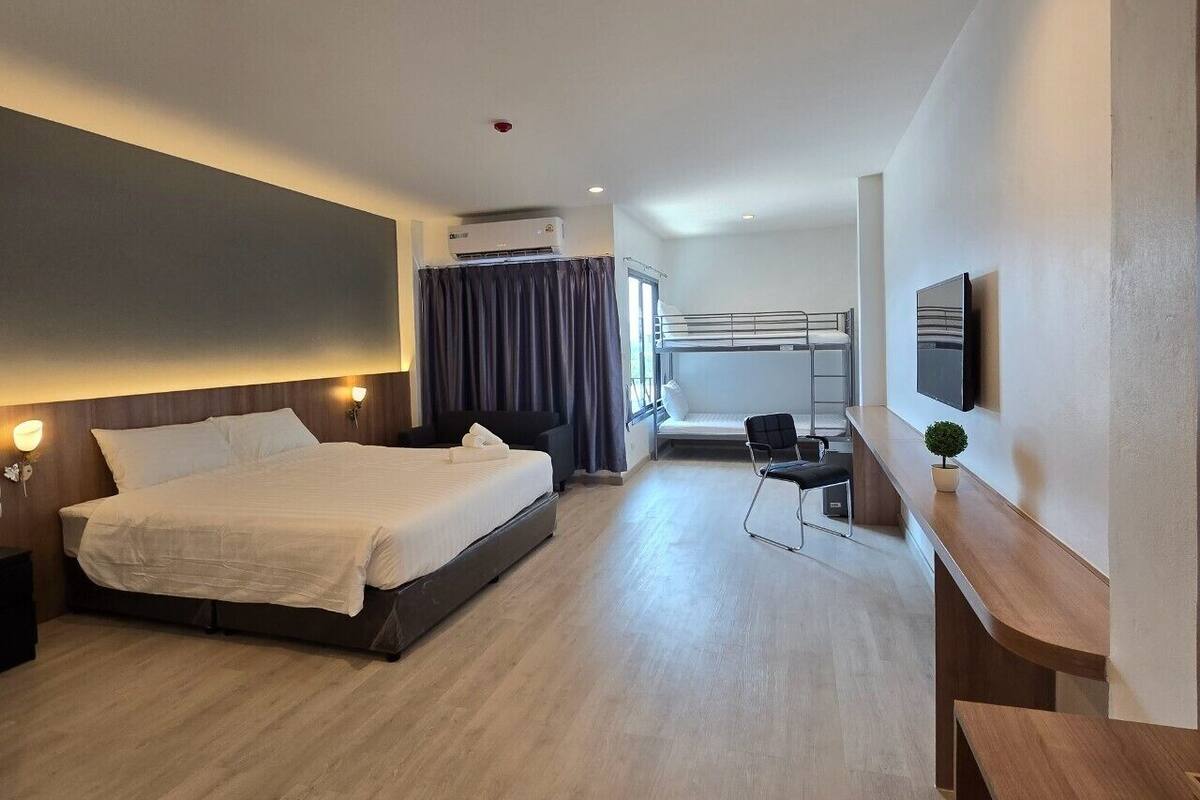 A modern hotel room with a large bed, a desk, and a TV.