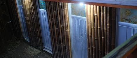 A row of bunk beds with a bamboo fence and a window with a floral design.