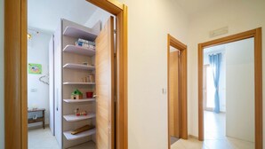 Un pasillo con una puerta de madera que da a una habitación con piso de baldosas blancas y un marco de puerta de madera.