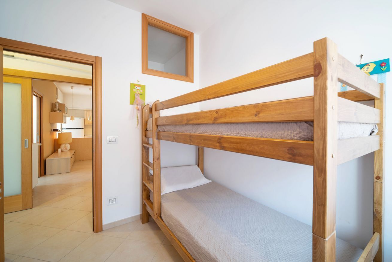A bunk bed in a room with a door leading to a bathroom and a kitchen.