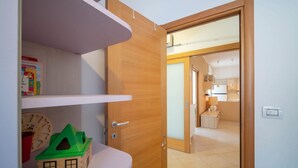 Una habitación con puerta de madera, repisa blanca y una pequeña casa de juguete verde.