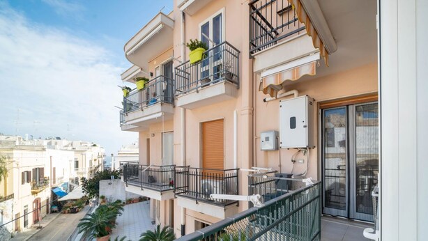 Un edificio residencial de varios pisos con balcones, asientos al aire libre y vista a la calle.