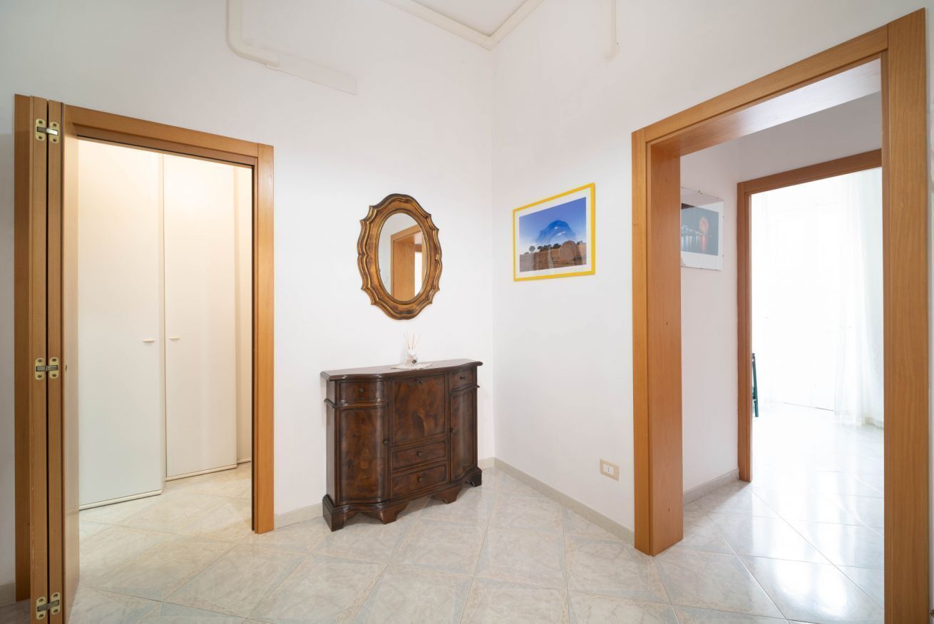 A hallway with wooden doors, a wooden cabinet, a mirror, and a framed picture on the wall.