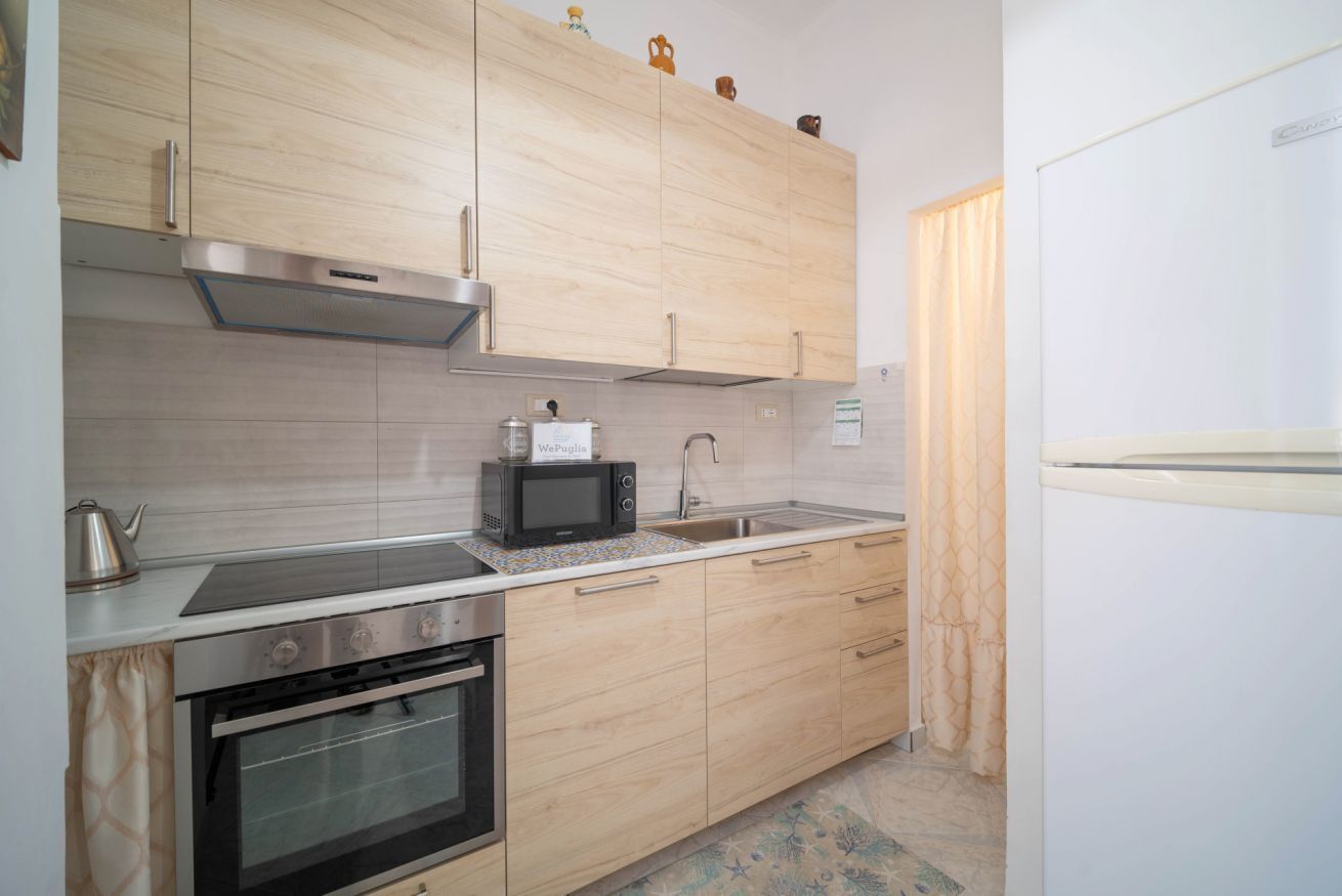 Een moderne keuken met houten kastjes, een magnetron, een waterkoker en een roestvrijstalen spoelbak.