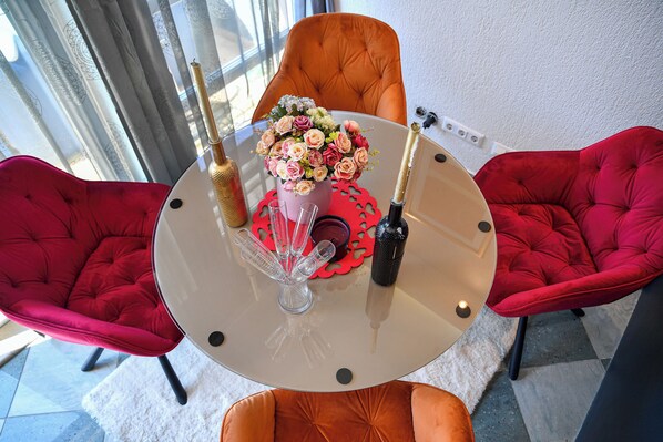 Un comedor moderno con una mesa de vidrio, sillas tapizadas en rojo y un jarrón con flores.