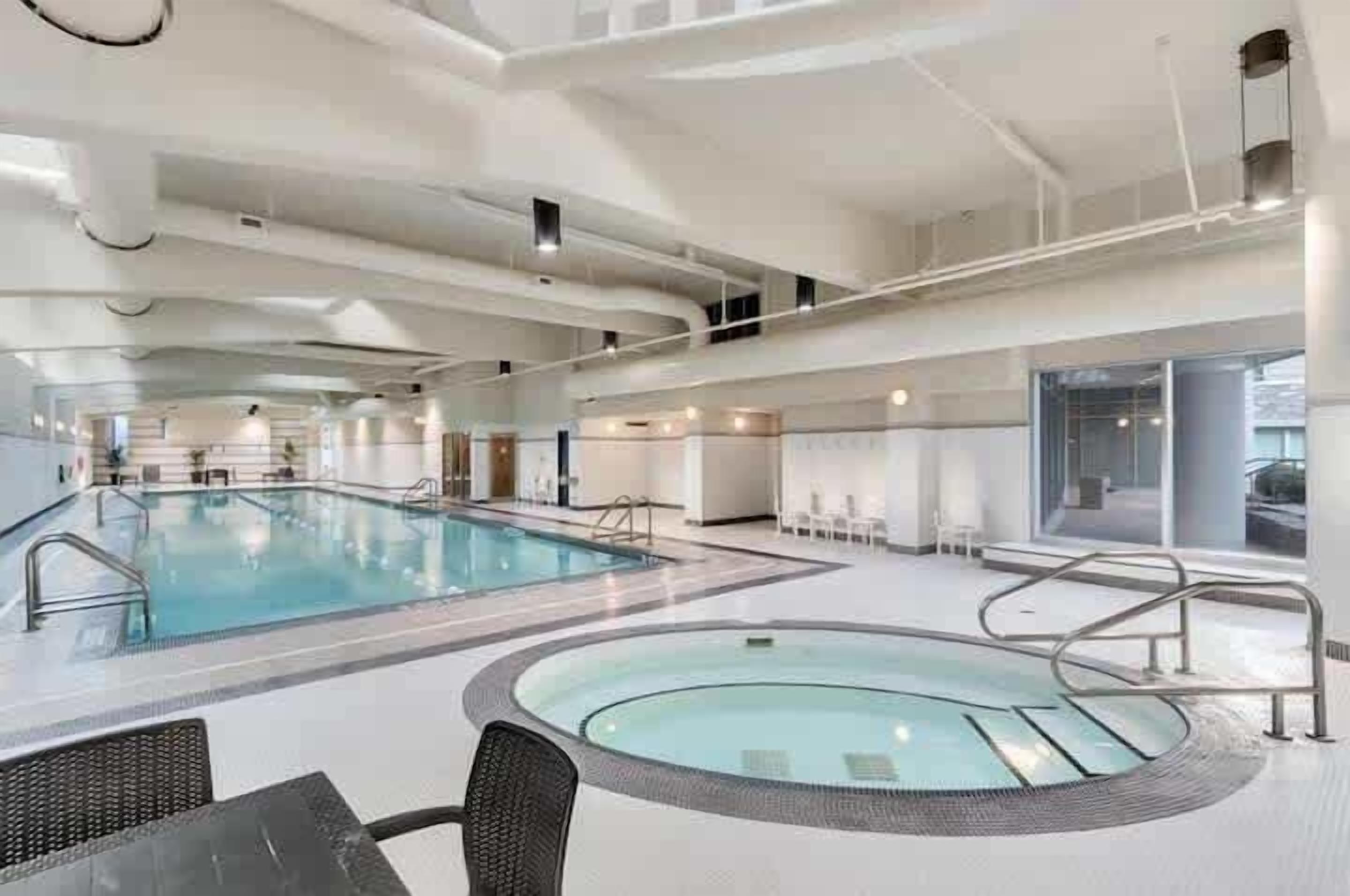 Een overdekt zwembad met meerdere banen, een zitgedeelte en een aparte whirlpool.