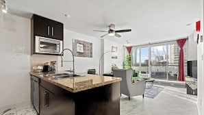 Een moderne keuken met een ingebouwde magnetron, een groot eiland met een spoelbak en een plafondventilator.
