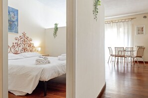 Hotellihuone, jossa on sänky, pöytä tuoleineen ja ikkuna, jossa on verhot.