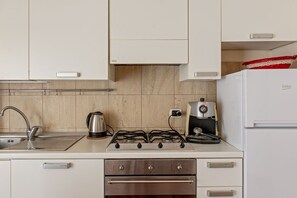 A kitchen with a gas stove, a coffee maker, and a refrigerator.