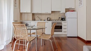 Una cucina compatta con mobili bianchi, un forno in acciaio inossidabile e un frigorifero bianco.