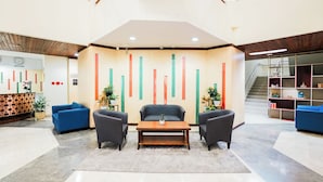 A lobby with a reception desk, blue seating, a coffee table, and a staircase in the background. - UTC Dago Hotel Bandung (Bandung)