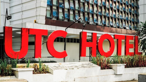 A hotel entrance with large red letters spelling "UTC HOTEL" and a modern building facade with patterned windows. - UTC Dago Hotel Bandung (Bandung)