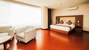 A hotel room with a bed, two armchairs, a small table, and a window with blinds. - UTC Dago Hotel Bandung (Bandung)