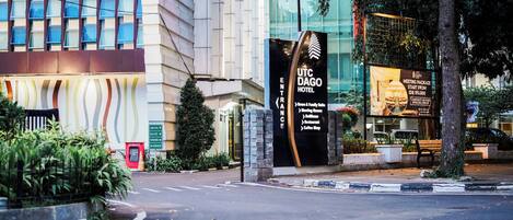 Entrada del Hotel UTC Dago, con un cartel que indica servicios como paquetes para reuniones, habitaciones y suites familiares, restaurante y cafetería.