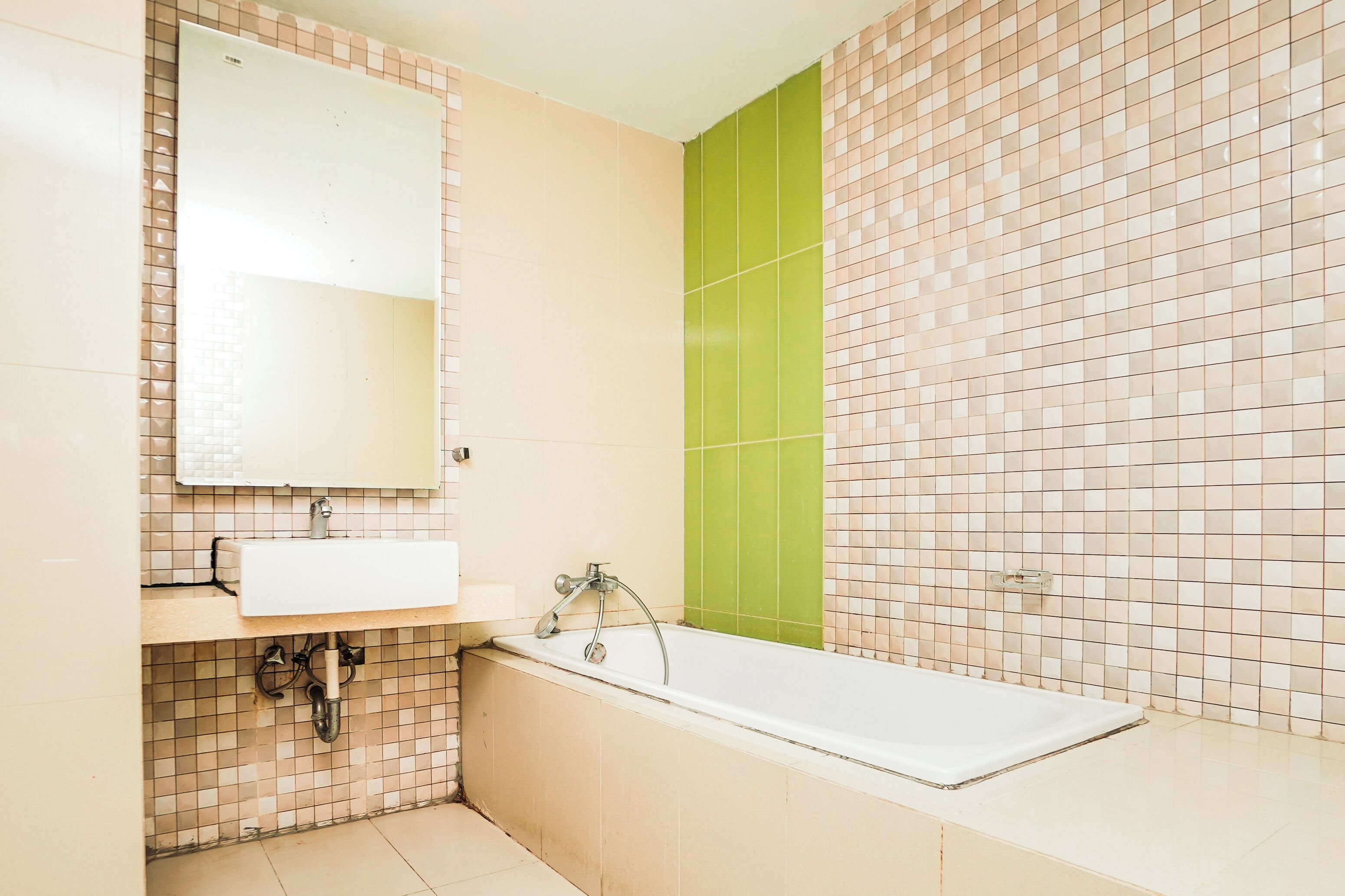 A bathroom with a sink, mirror, and bathtub.