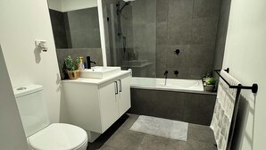 Een moderne badkamer met toilet, wastafel en bad.