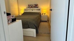 Een kleine hotelkamer met een bed, nachtkastjes en een klein vloerkleed.