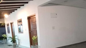 A building with a flat roof, white walls, and a tiled floor. There are potted plants near the entrance and a door with a wooden frame. - Lanka Global  (Jaffna)