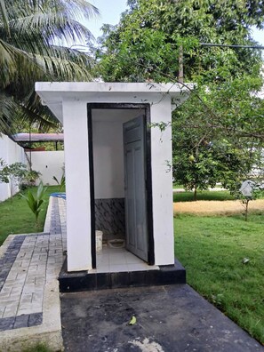 A small, white, single-room structure with a door, a tiled floor, and a concrete base. - Lanka Global (Jaffna)