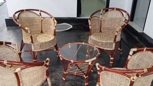 A set of wicker chairs and a glass table arranged on a dark floor, likely in a lobby or entrance area. - Lanka Global  (Jaffna)