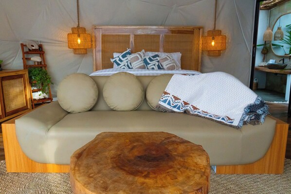 A cozy tent-style room with a sofa bed, two hanging lamps, a wooden side table, and a small plant. - Gamat Bay Resort (Penida Island)