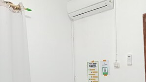 Ein kleines Büro mit Schreibtisch, Stuhl und einer Klimaanlage an der Wand.