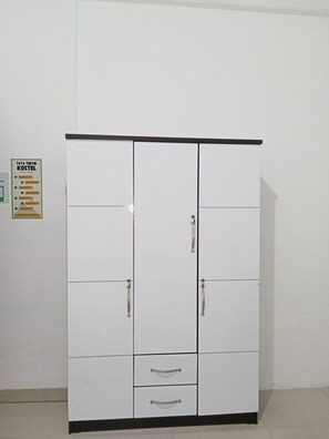 Une armoire blanche avec deux tiroirs et deux portes, un plan de travail noir et un panneau sur le mur, à gauche.