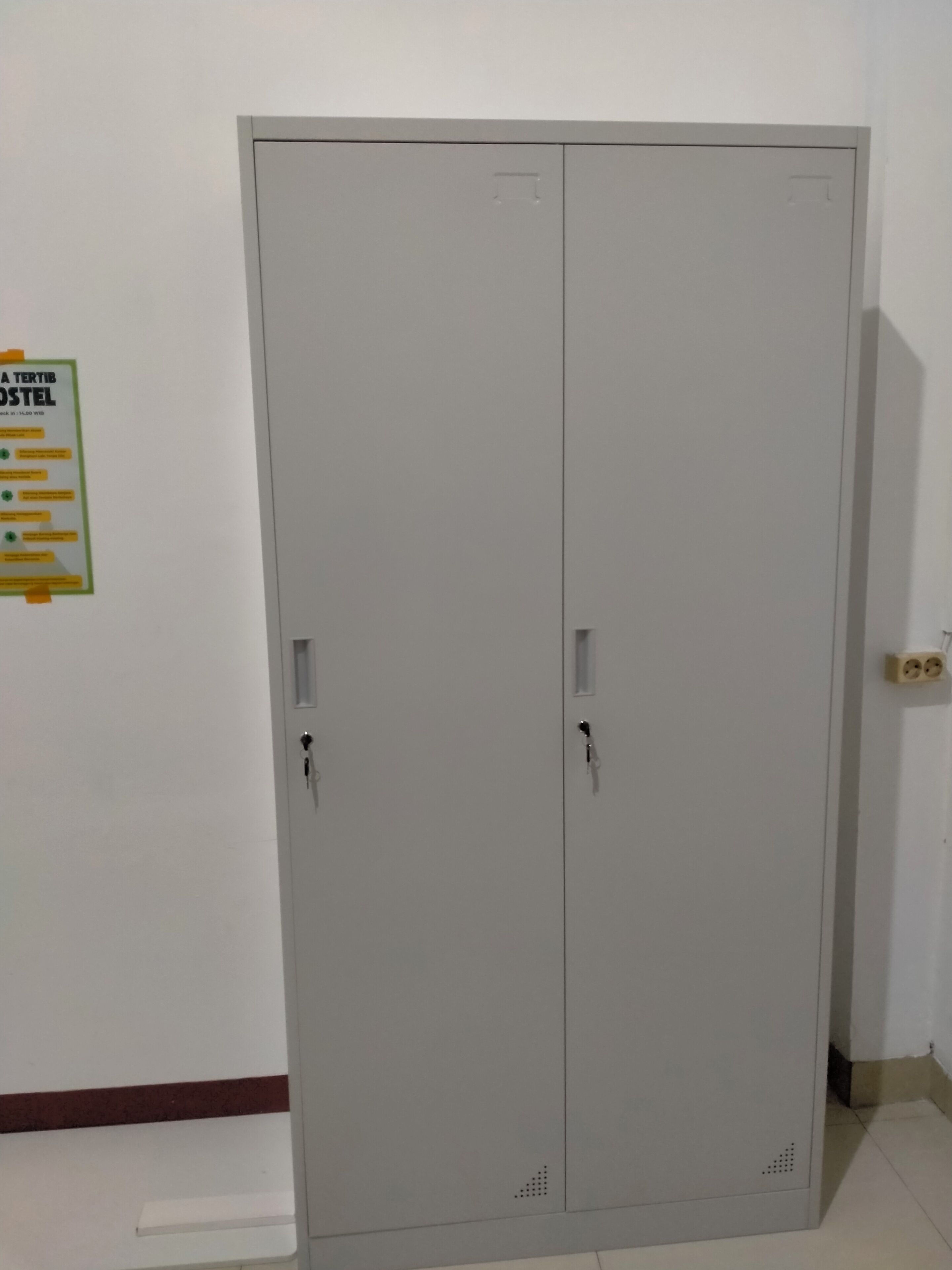 A grey double wardrobe with two doors and a small shelf at the bottom.