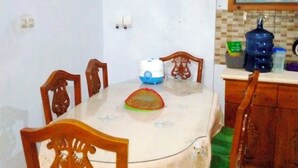 Ein Essbereich mit einem runden Tisch, Stühlen, einer Mikrowelle und einem Wasserspender.