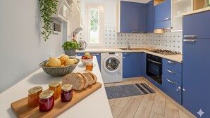 A modern kitchen with blue cabinets, a washing machine, and a countertop with bread and jars. - Apartment with A/C and parking space | Ap12 (Imperia)