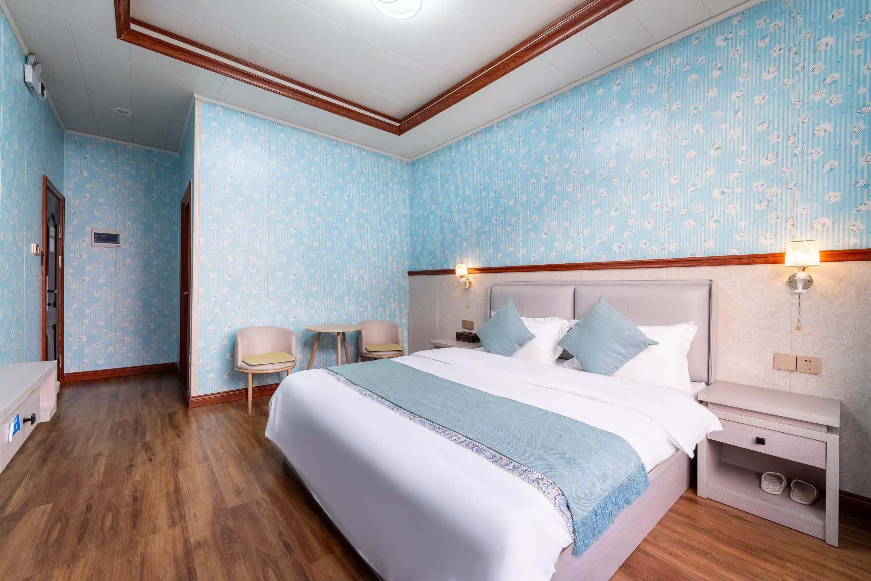 Una habitación de hotel con una cama grande, mesitas de noche, una silla y una pequeña mesa.