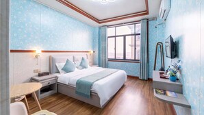 Habitación de hotel con cama, mesita de noche, silla y un pequeño escritorio con lámpara.