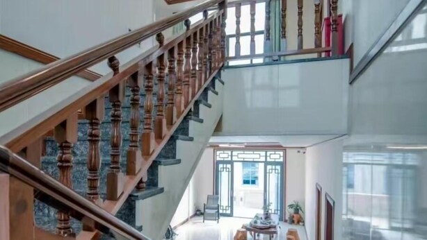 Una majestuosa escalera de madera con barandilla que lleva al segundo piso.