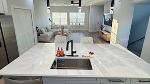 A modern kitchen with a large island, grey cabinets, and pendant lighting. - Luxury, Brand NEW 4BR/3.5BA Townhome I South Tampa Gem I Central Location (Tampa)