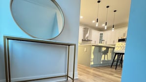 A modern kitchen with white cabinets, a stainless steel range hood, and a bar stool. - Luxury, Brand NEW 4BR/3.5BA Townhome I South Tampa Gem I Central Location (Tampa)