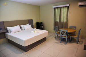 Una habitación de hotel con cama, una pequeña mesa con sillas, aire acondicionado y televisor.